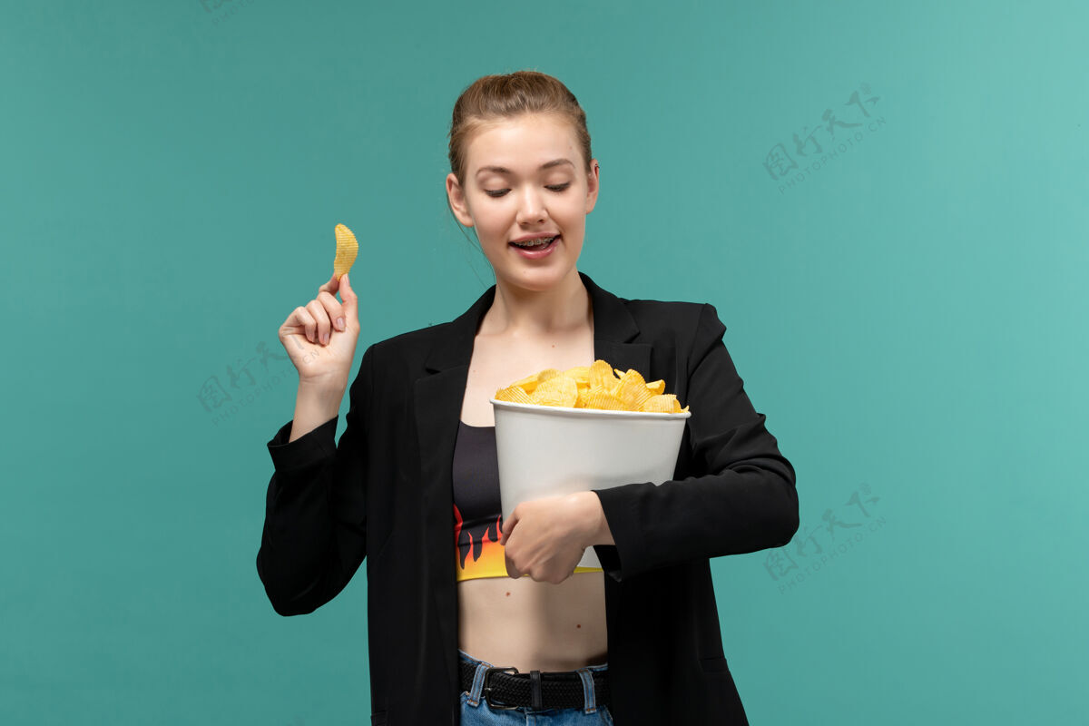 女正面图：年轻的女性拿着薯片在蓝色的桌子上看电影西装男电影