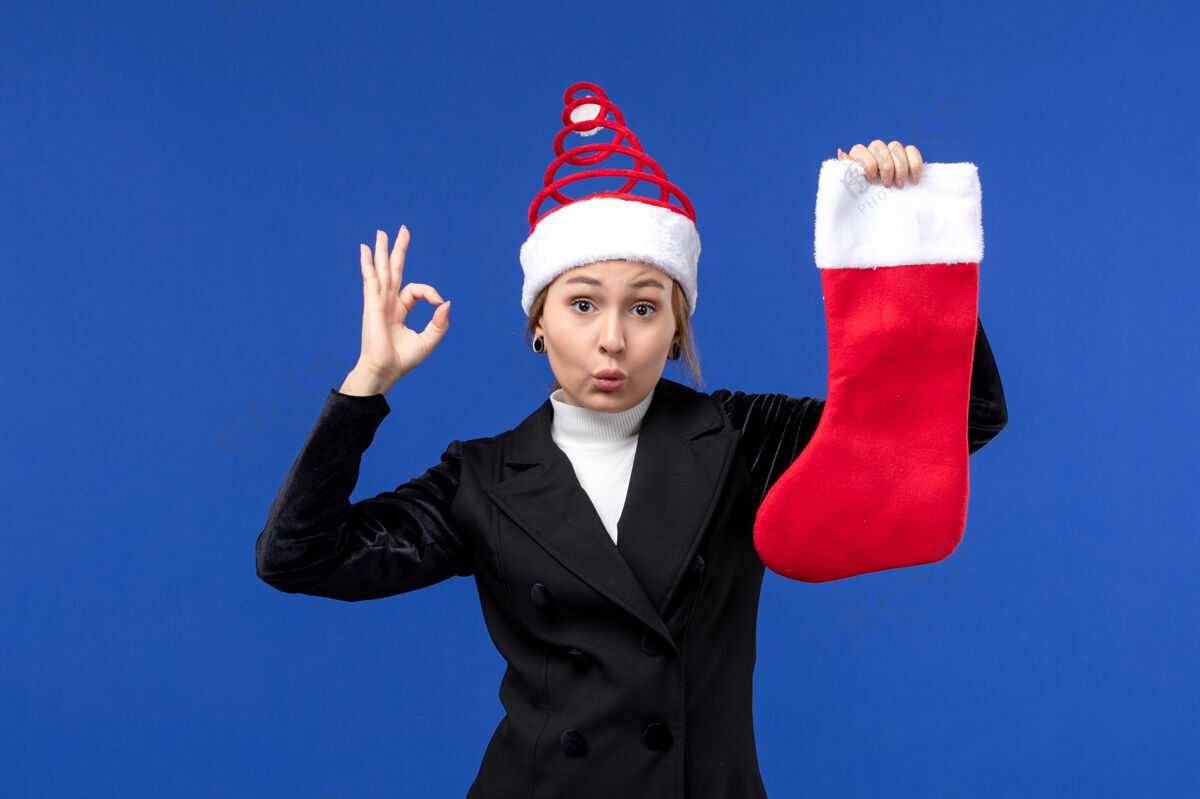 专业正面图：年轻女子手持红色圣诞袜在蓝色墙壁上过年观点成人成功