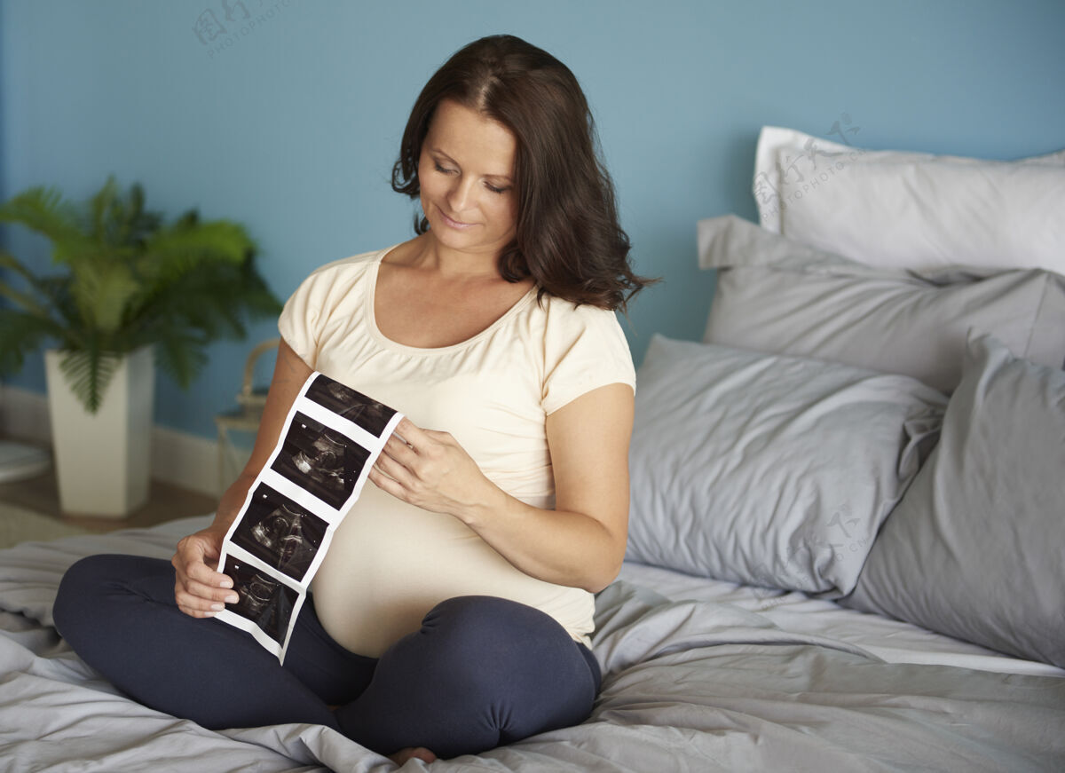 怀孕孕妇浏览她的宝宝的超声波图像预期床后代