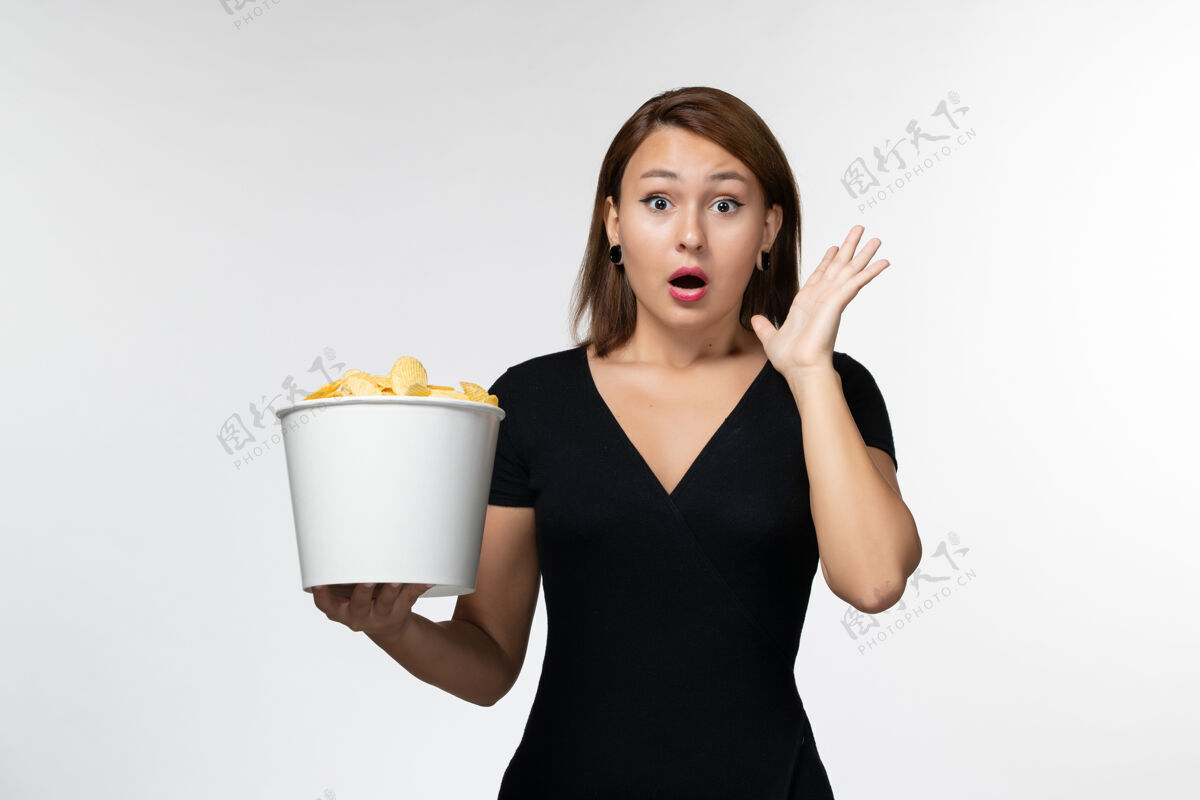 电影院正面图年轻的女性拿着土豆片和震惊的篮子在白色的表面年轻的女性剧院土豆
