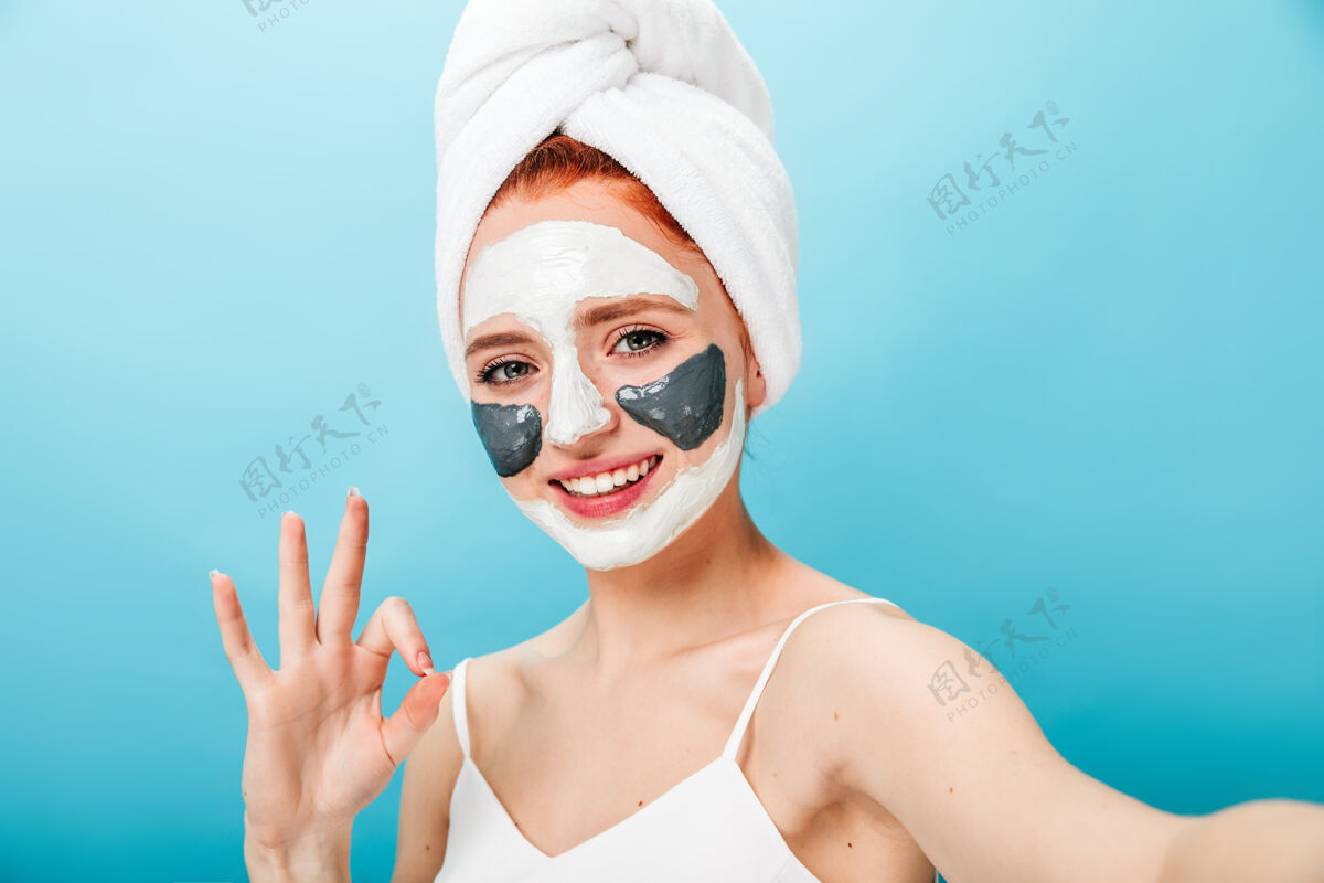 面膜戴着口罩的女人 表情很好 笑着说女模特一边做水疗一边自拍大笑毛巾完美皮肤