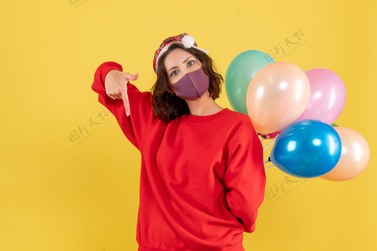 表演正面图：年轻女子把气球藏在黄色桌子上的无菌面具里气球喜剧演员隐藏