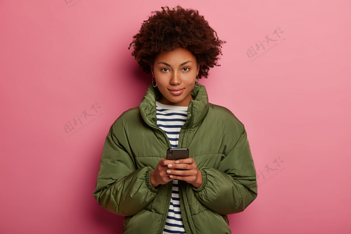 民族一个留着非洲发型 穿着条纹套头衫和冬季夹克的女人信息黑发条纹