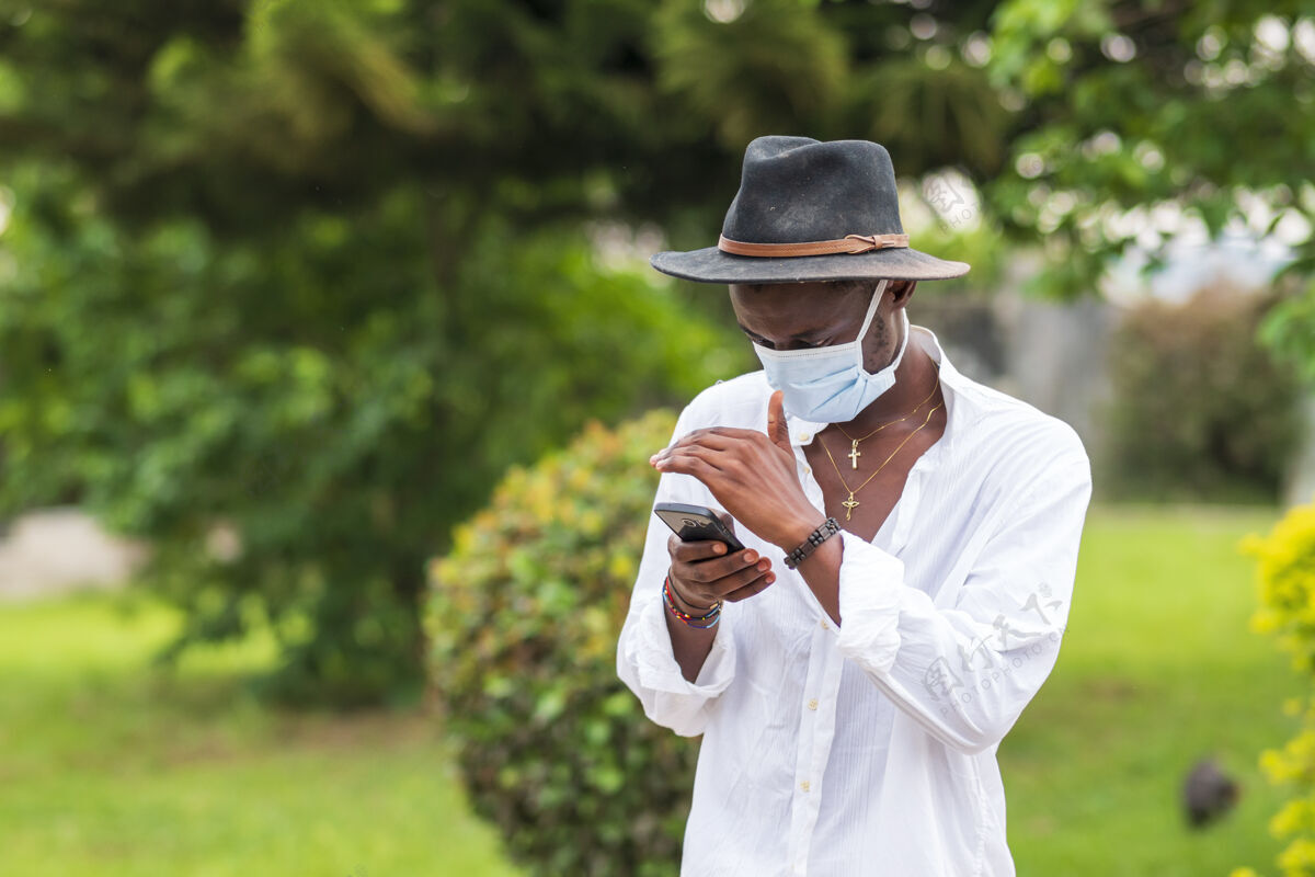 男性戴着防护面罩的年轻人在户外用手机流行病休闲医疗