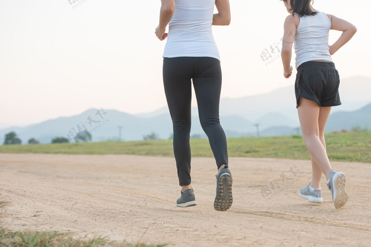 能量两位女性跑步者在秋天的森林里户外慢跑家庭快乐孩子