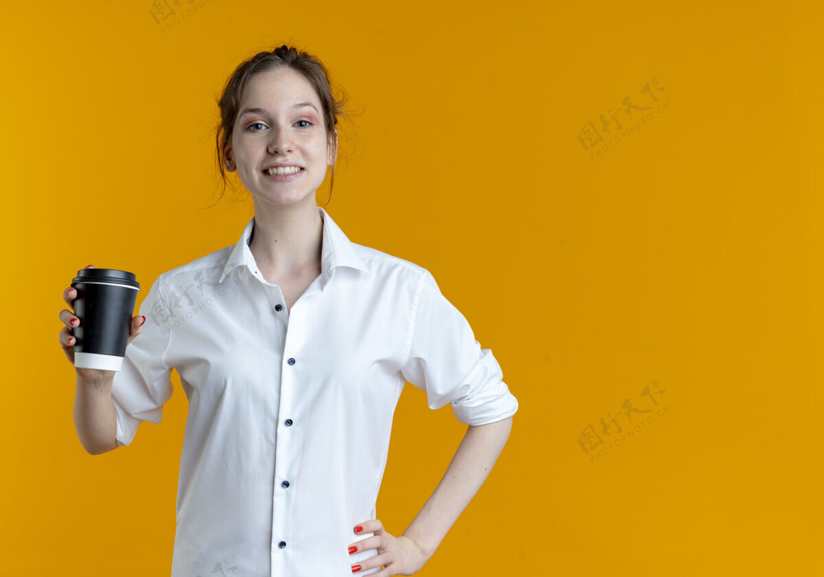 复制年轻微笑的金发俄罗斯女孩拿着咖啡杯在橙色空间与复制空间隔离女孩微笑咖啡