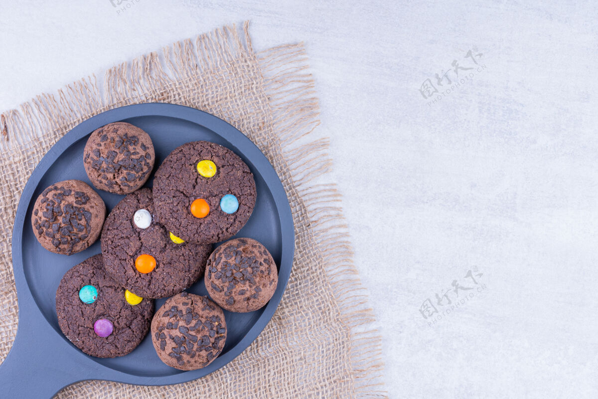 平铺巧克力饼干放在麻布上的木制平底锅上 放在大理石桌上甜点顶视图五颜六色