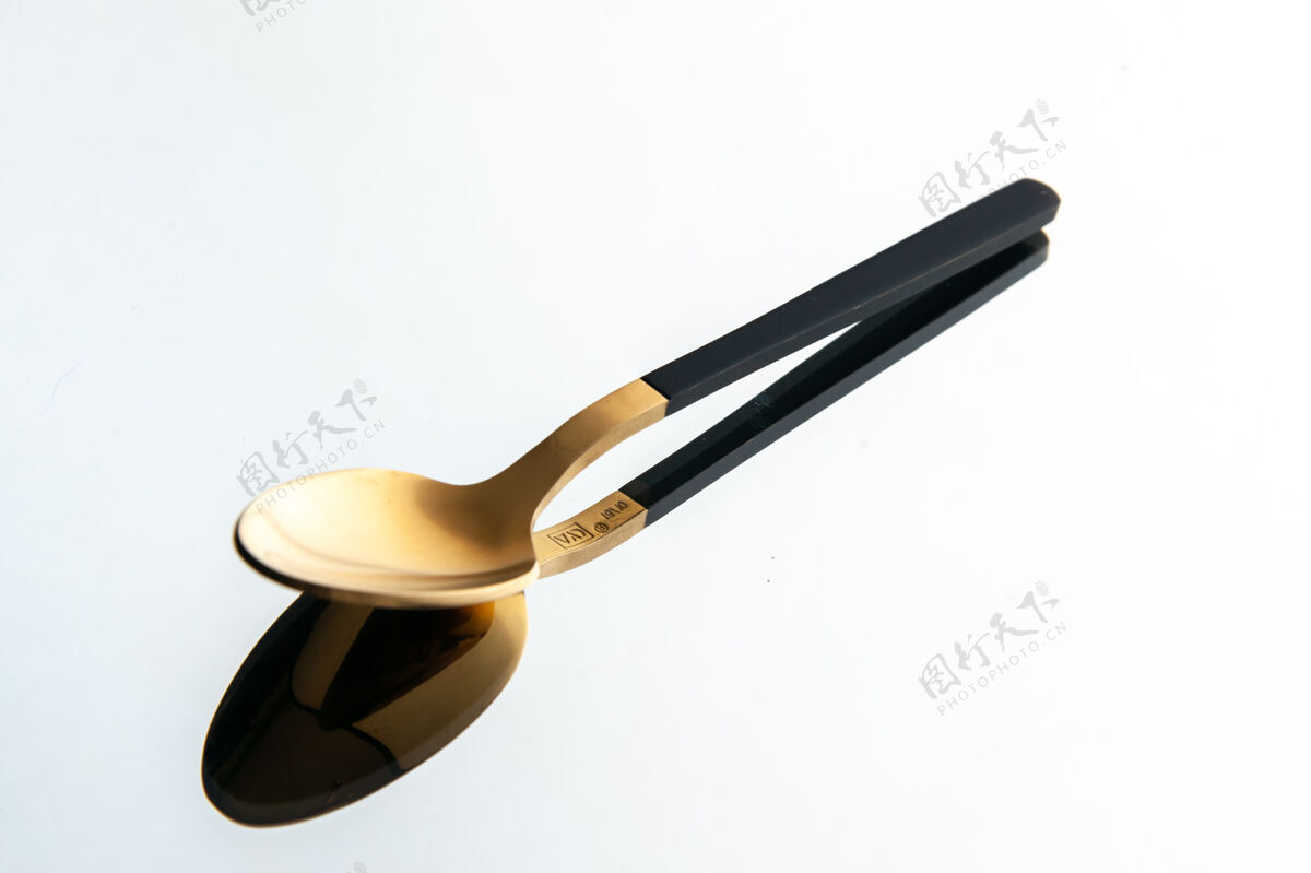 桌子白色背景上的金色勺子的前视图厨具金匙厨房