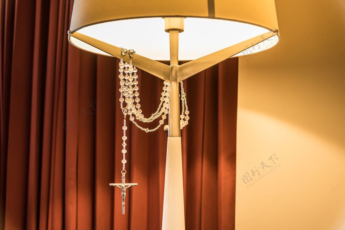 设计床头灯的垂直镜头 上面挂着一个银十字架 在灯光下闪闪发光基督颜色灯