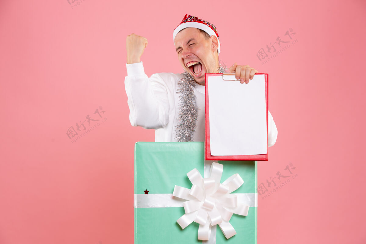 文件正面图年轻男性在粉色背景上手持文件欢庆持有礼物礼物