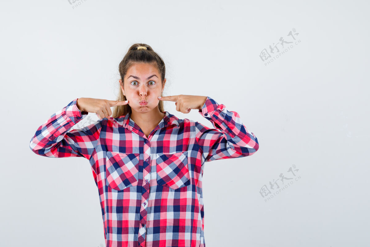 检查照片中的年轻女士穿着格子衬衫 手指按在吹皱的脸颊上 看上去很滑稽有趣自然年轻