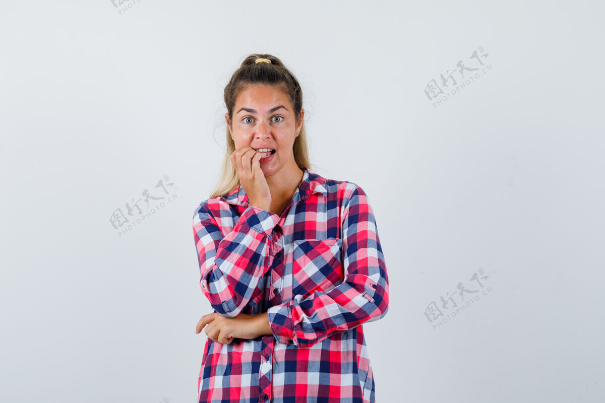 黑发在格子衬衫里咬指甲的年轻女士的画像 看起来很麻烦的前视图咬视图女性