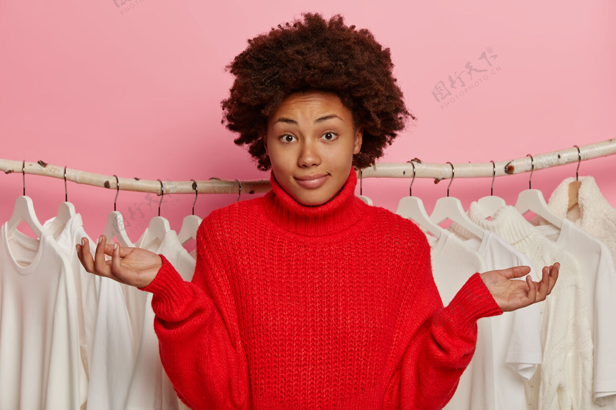 女性非裔美国女士穿什么衣服 在衣柜附近摆姿势时耸耸肩 衣架上有衣服非洲女士穿