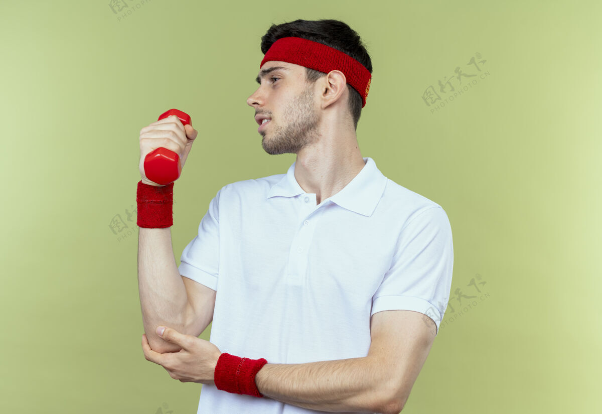 年轻戴着头巾的年轻运动型男子戴着哑铃锻炼身体 看起来比绿色更自信看哑铃绿色