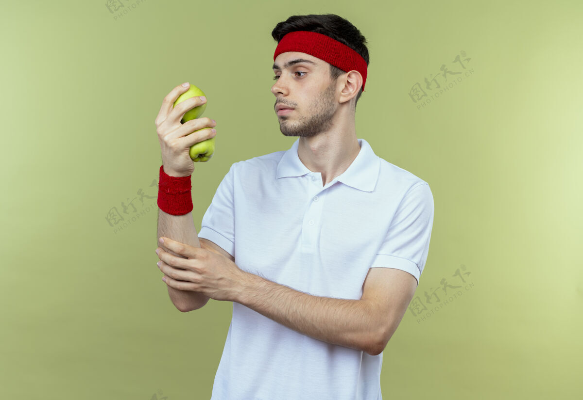 苹果戴着头巾的年轻人举着两个绿色的苹果 神情严肃地看着他们两个抱着运动