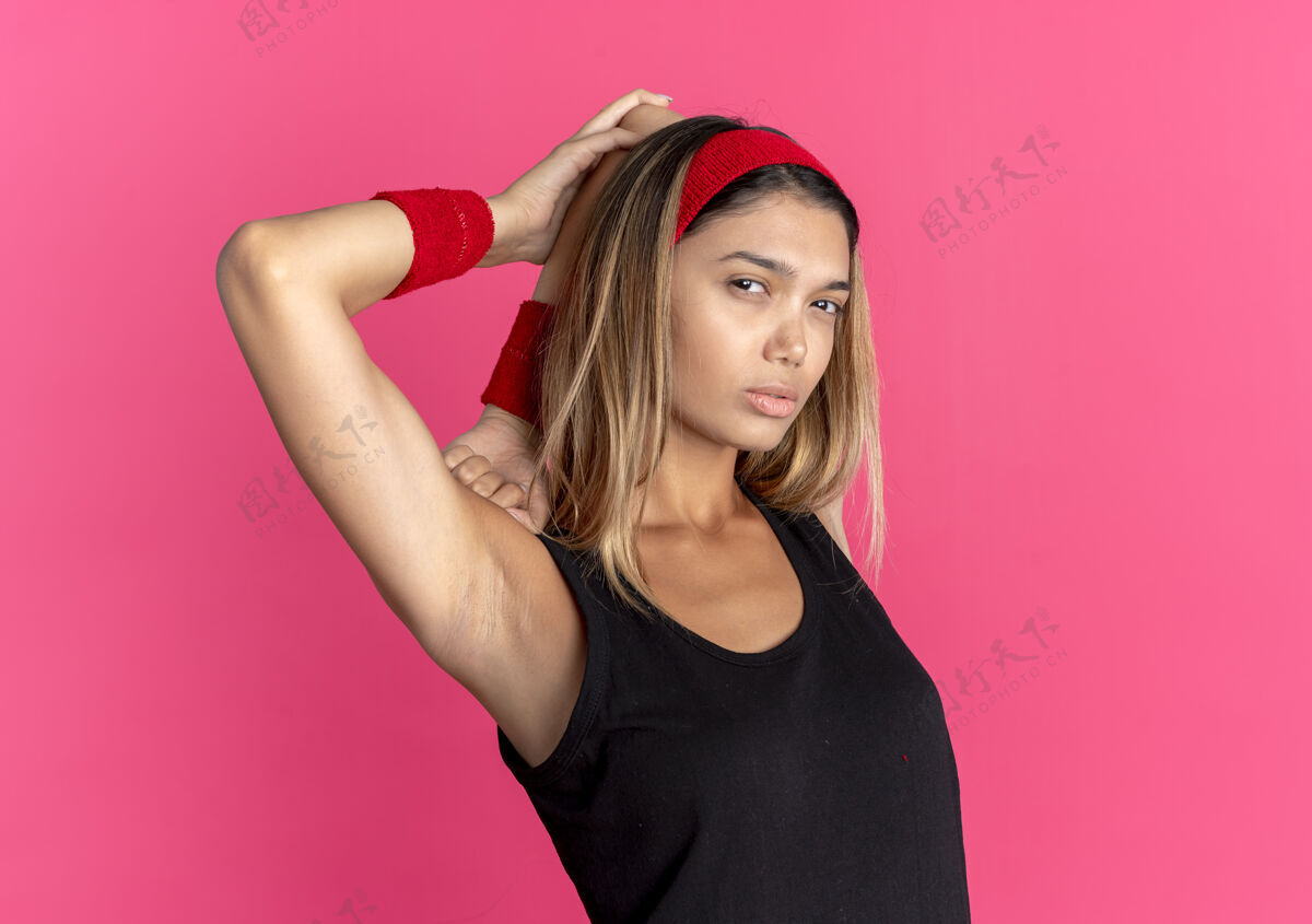 黑色身穿黑色运动服 头戴红色头带的年轻健身女孩 看上去自信满满地伸展着身体健康伸展长相