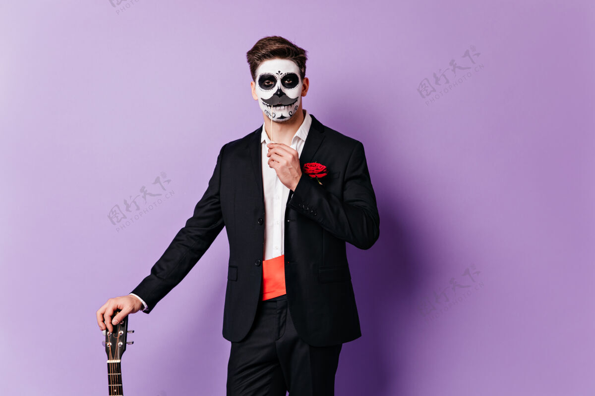 玫瑰一个穿着经典西装 脸上涂着颜料的家伙 留着假胡子 靠着吉他摆姿势面部艺术节日骷髅