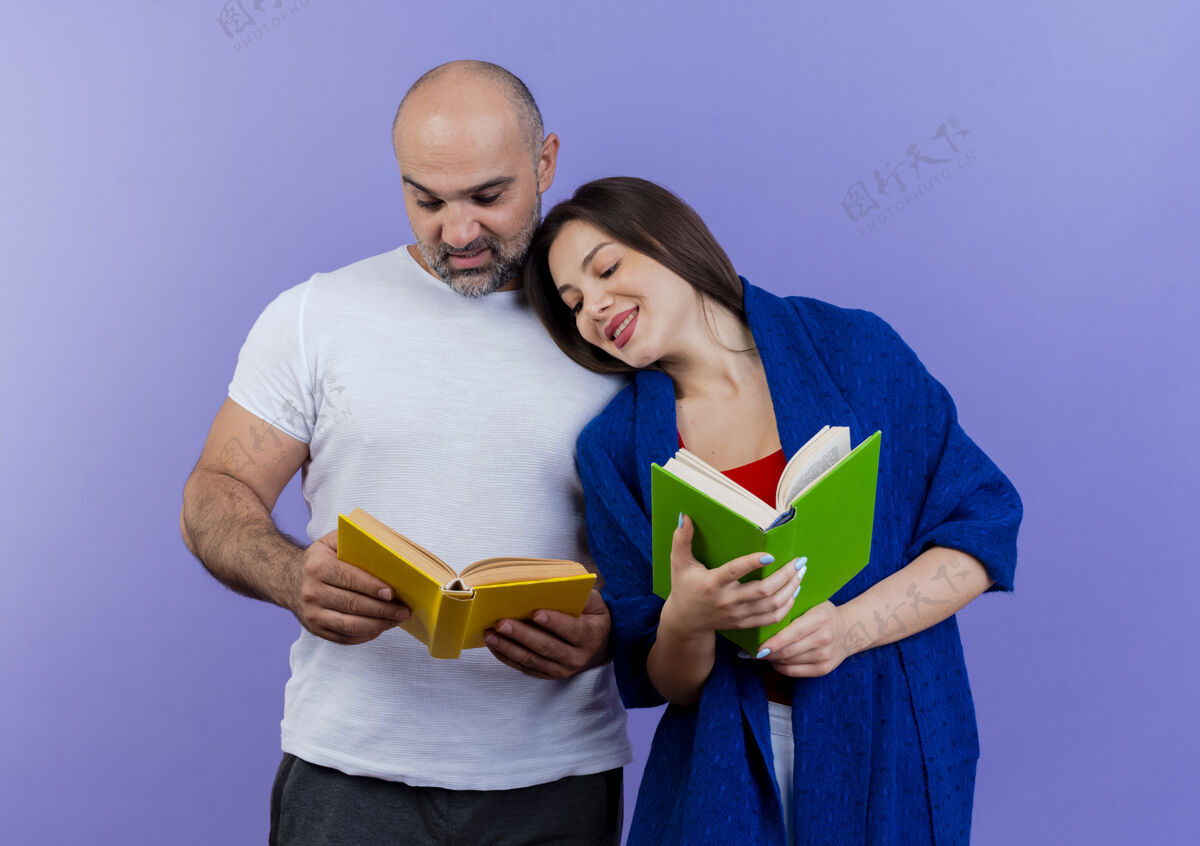成人的高兴的成年夫妇女人裹着披肩 一边拿着书 一边看着男人的书 女人把头靠在他的肩膀上两个请书