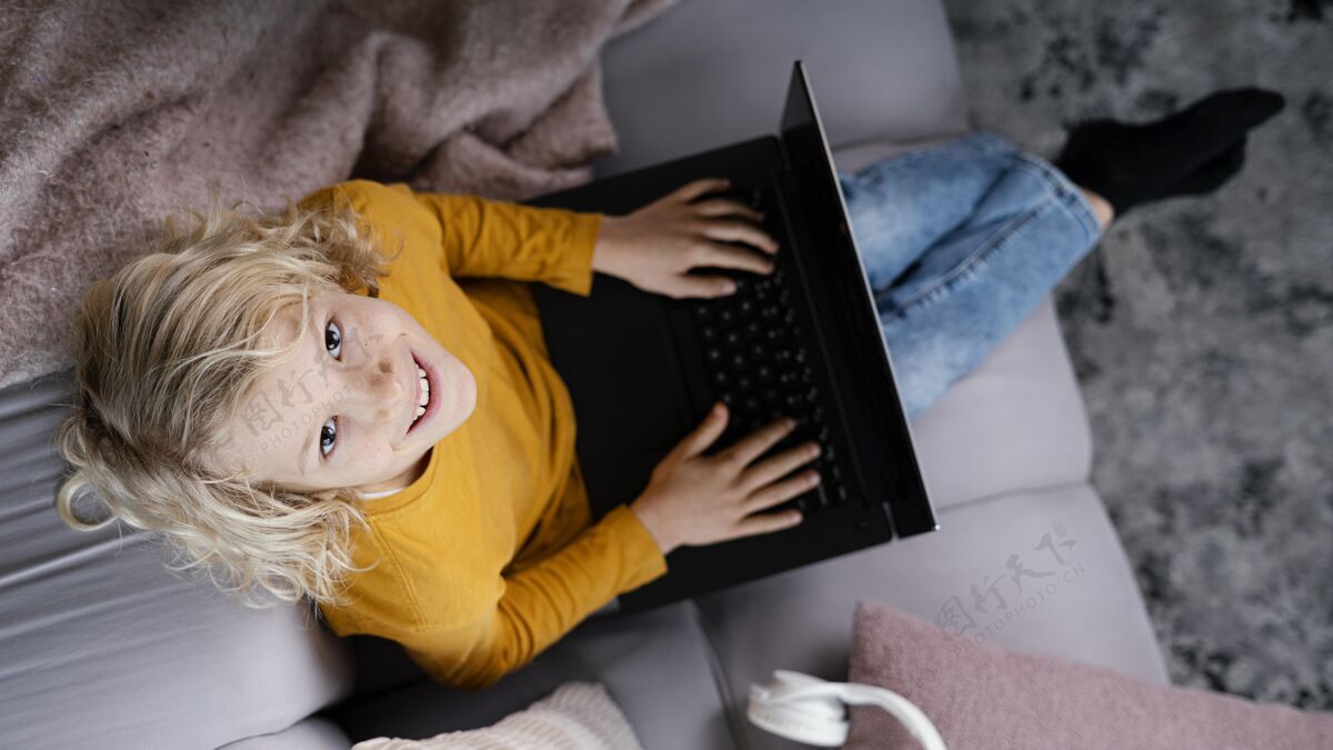 笔记本电脑坐在沙发上拿着笔记本电脑的男孩设备技术房子