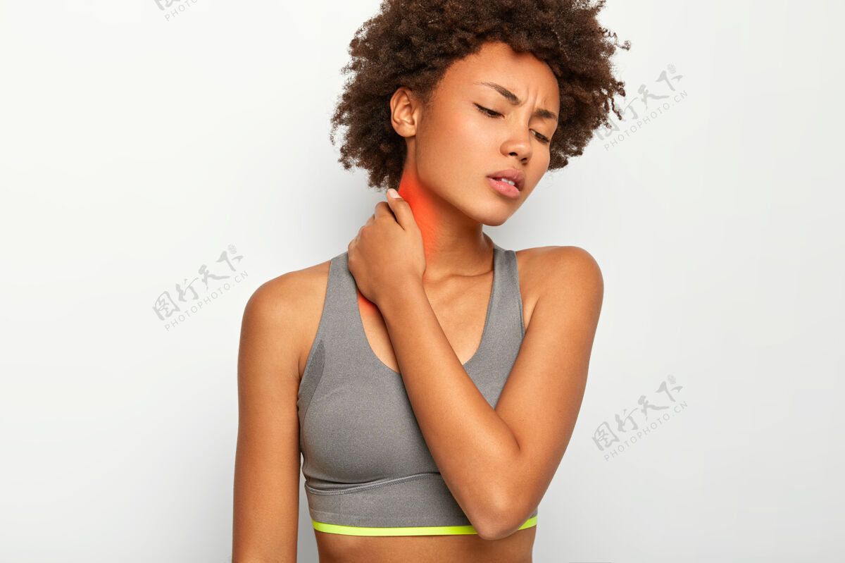 医学心烦意乱的卷发女青年患有颈部疼痛 在运动训练中受伤 穿着休闲的灰色上衣年轻理发痉挛