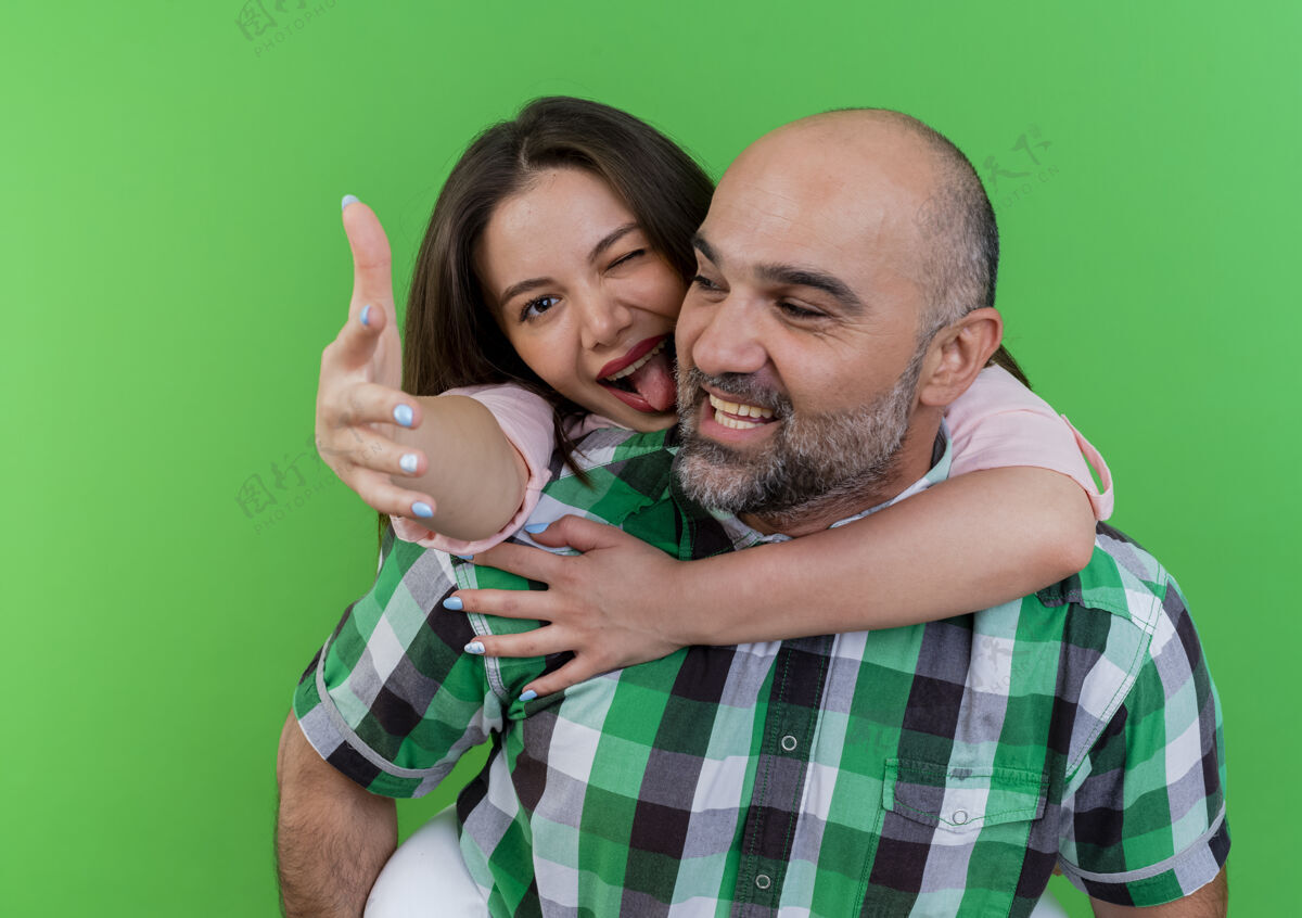 手快乐的成年夫妇男人看着背上抱着女人的女人眨眼露出舌头伸出手来喜悦看成人