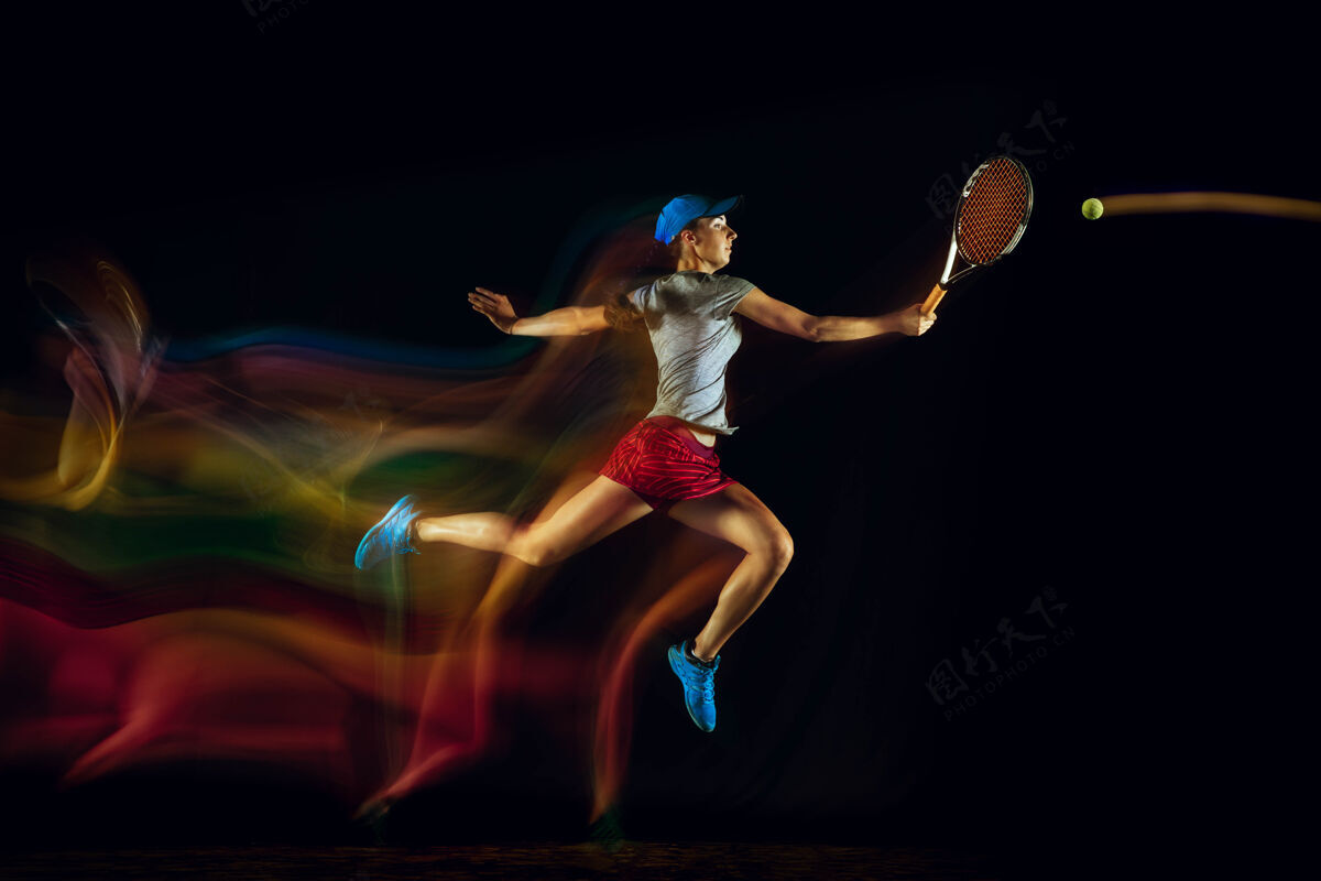 运动一位白人女子在黑色的墙壁上打网球 在混合和淡色的灯光下适合年轻的女性运动员在运动比赛中运动或行动运动的概念 运动 健康的生活方式网球活动女子