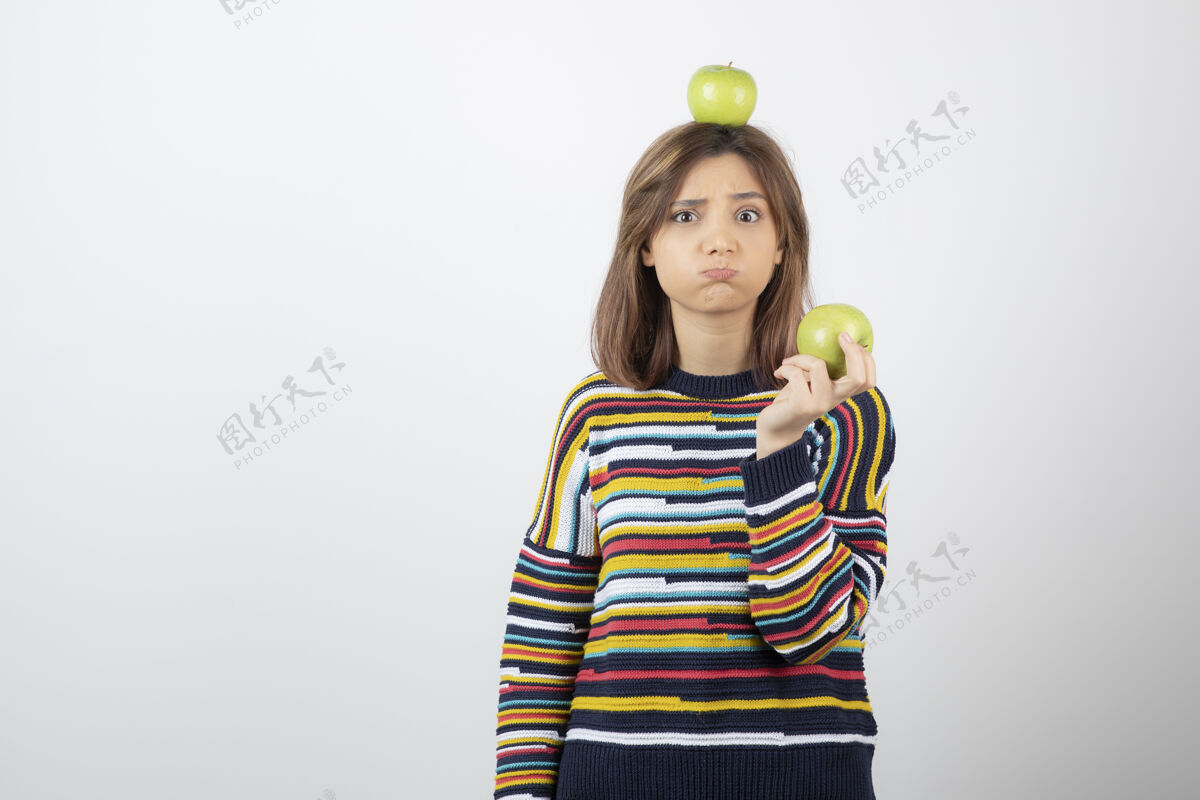 苹果一个穿着便服的可爱的年轻女子 手里拿着青苹果 满脸愁容健康肖像模特
