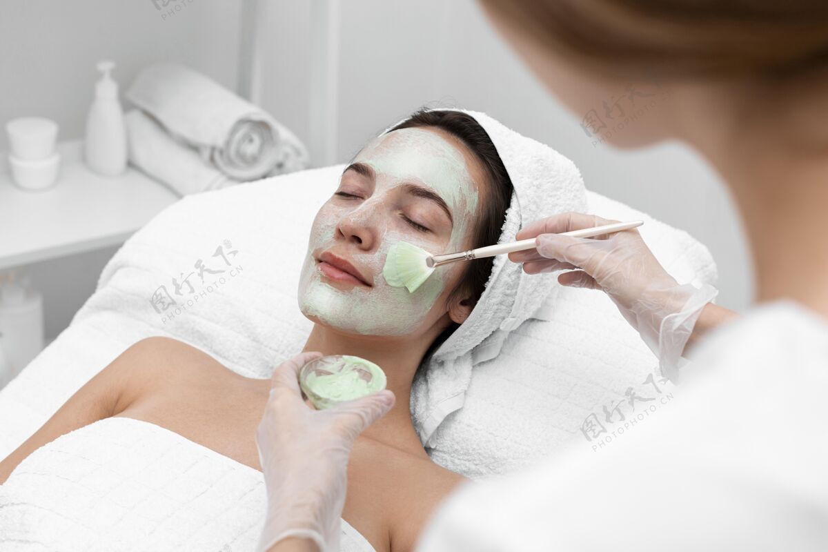 美容院美容师给女性客户敷面膜化妆品美容治疗治疗