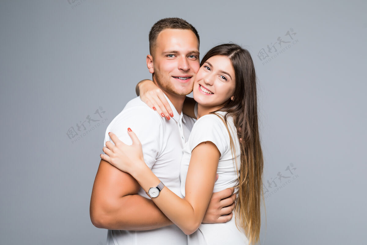 看一对身着白色T恤的年轻情侣浪漫友好地拥抱在一起感情人女性