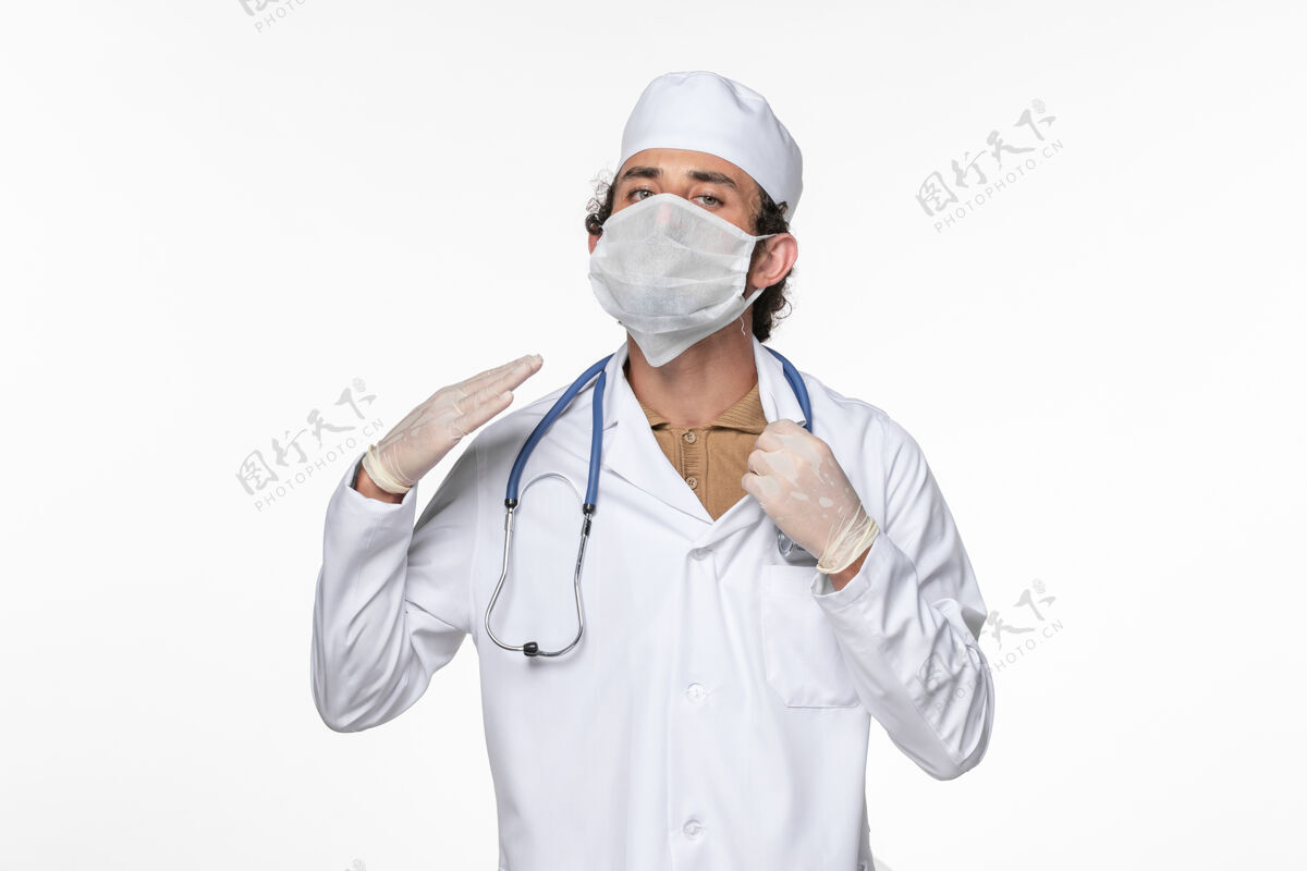 医生正面图男医生穿着医疗服 戴着无菌口罩 以防冠状病毒感染浅白桌上的冠状病毒大流行疾病健康专业冠状病毒男性