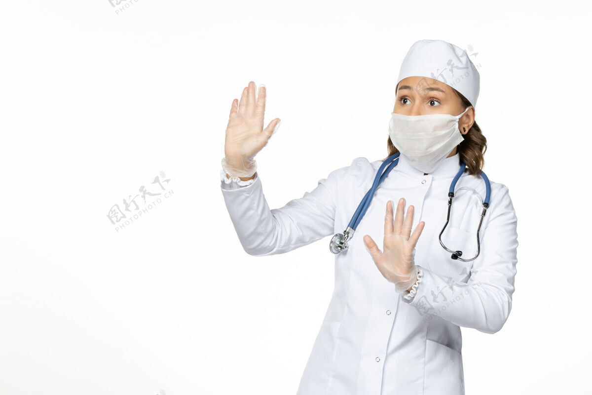 冠状病毒正面图女医生身穿白色医疗服 戴口罩 因白色办公桌上有冠状病毒大流行性疾病隔离冠状病毒面罩专业人员疾病