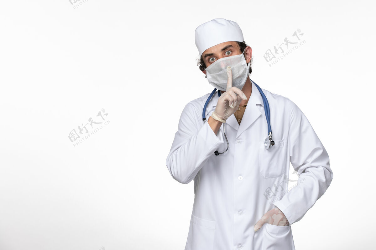 人前视图穿着医疗服的男医生戴着口罩 以防白墙病毒疾病传播疾病实验室外套衣服