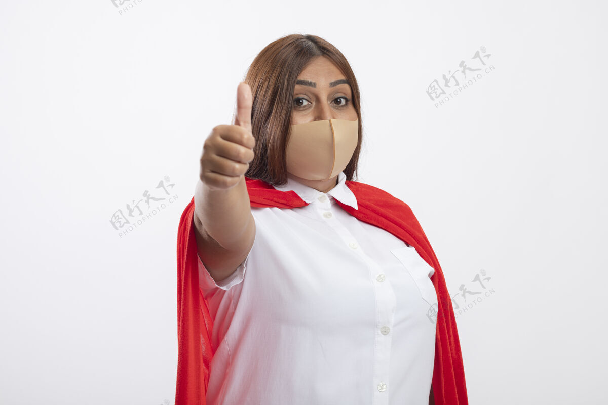 医疗高兴的中年女超人戴着医用口罩大拇指孤立地站在白色请中年穿