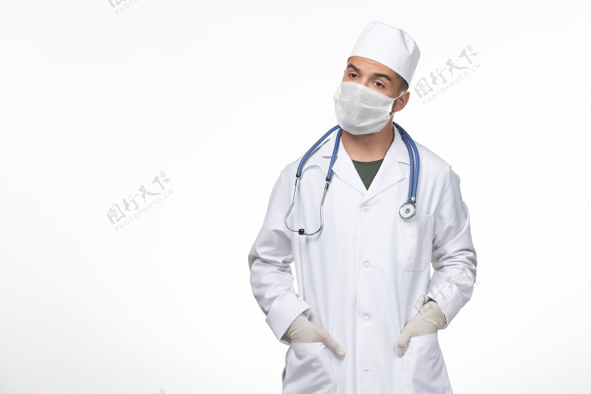 西装正面图：男医生穿着医疗服 戴着防冠状病毒面罩 在浅白的墙壁上进行冠状病毒疾病隔离大流行疾病专业面具