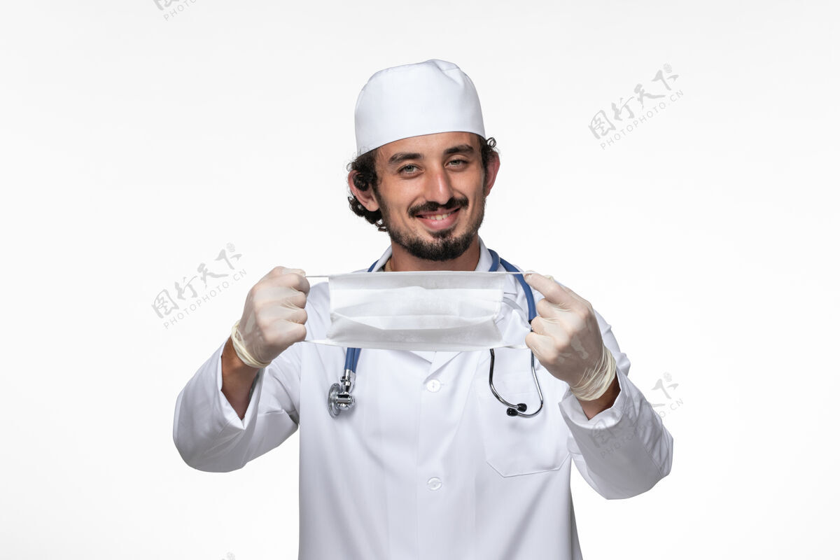大流行正面图：男医生穿着医疗服 戴着口罩 以防白墙病毒疾病传播医生专业医疗
