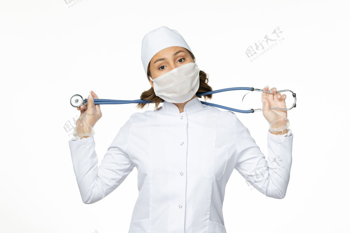 疾病正面图女医生穿着白色医疗服 戴着无菌口罩 在白墙上进行大流行性疾病药物病毒隔离面罩成人男性
