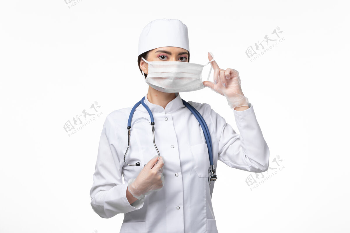 听诊器正面图女医生穿着白色无菌医疗服戴口罩因柯维德-白墙病柯维德-大流行病毒病专业外套女性