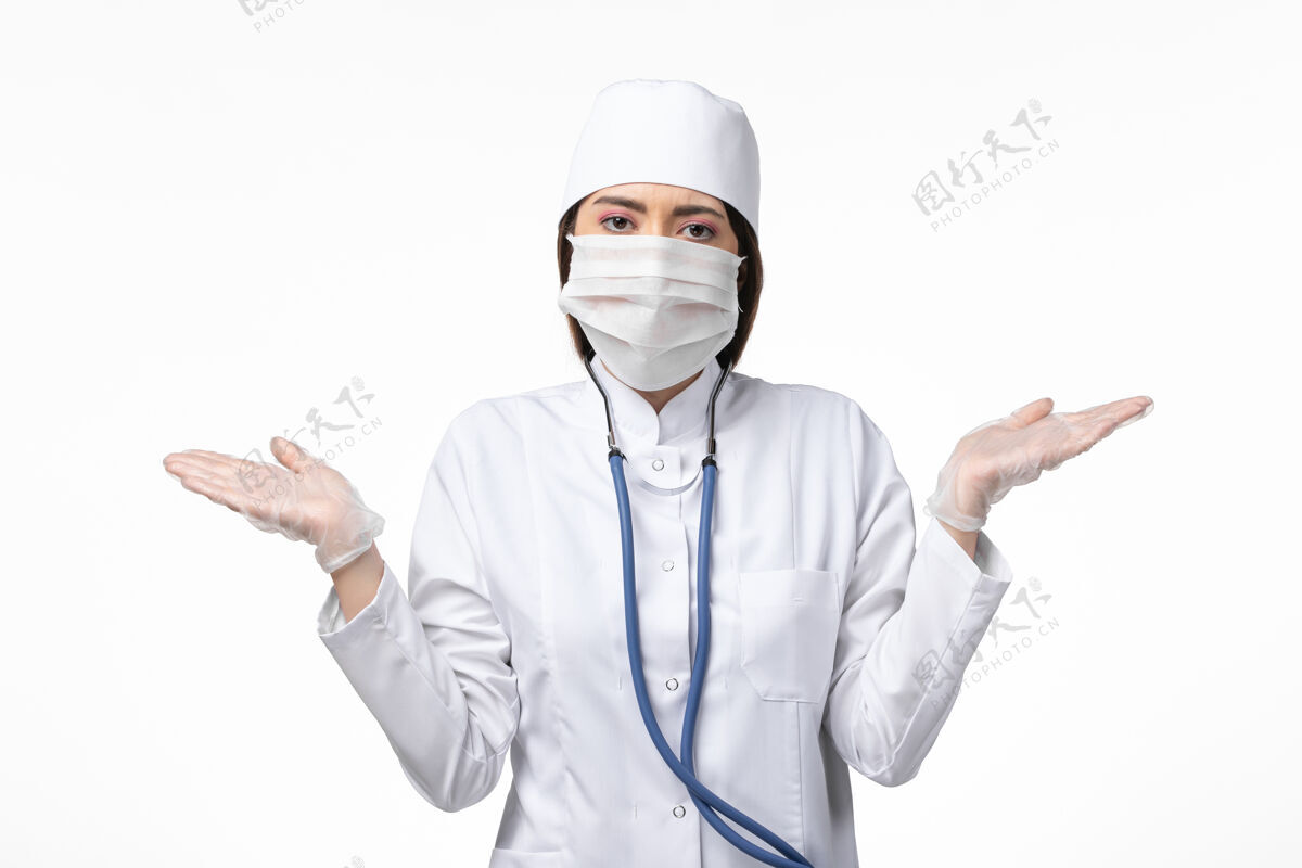 口罩正面图女医生穿着白色无菌医疗服带口罩因白墙上冠状病毒病大流行病毒covid-到期套装冠状病毒防护