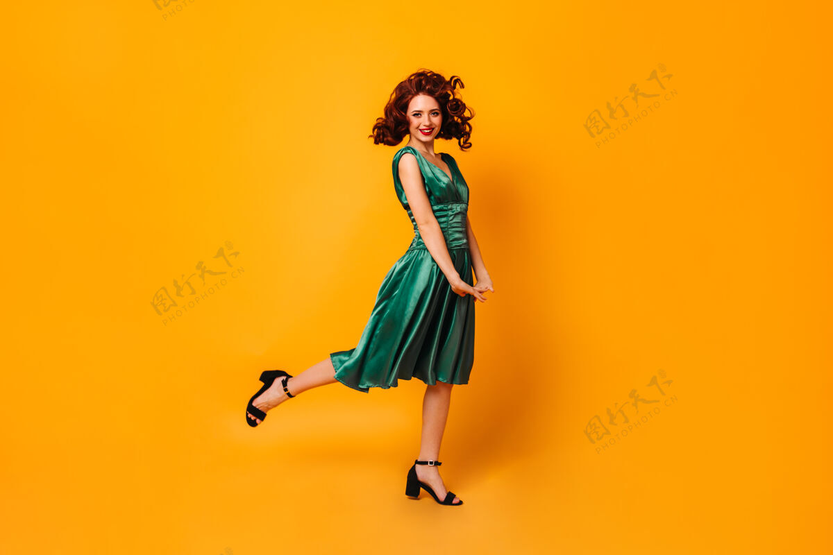 表情一只脚站着一个穿着绿色裙子的兴奋的健康女孩黄色空间里翩翩起舞的优雅女士的全貌魅力年轻人淑女