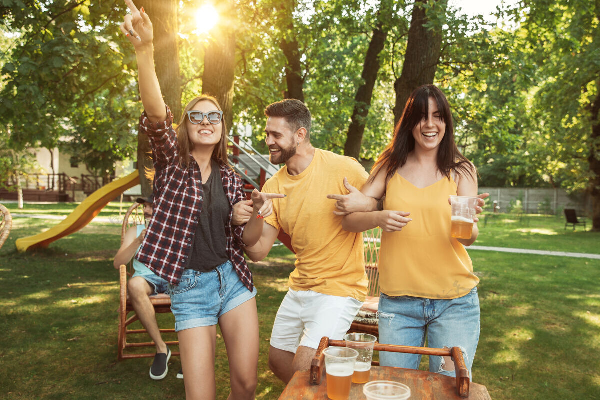 吃一群快乐的朋友在阳光明媚的日子里喝着啤酒 一起烧烤一起在户外的林间空地或后院休息干杯啤酒朋友