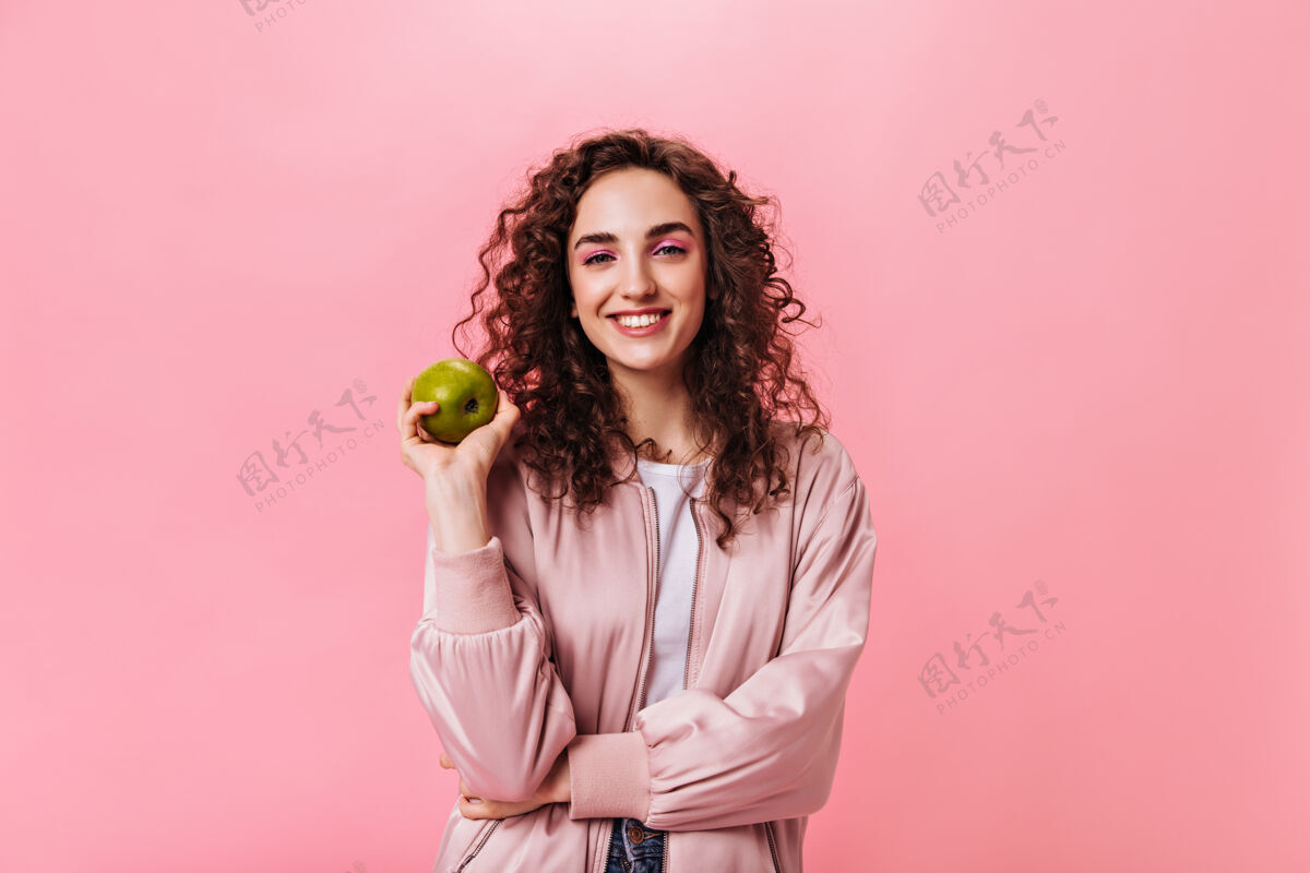 女人一个微笑的女人 穿着粉红色的衣服 手里拿着新鲜的苹果针织运动衫希望