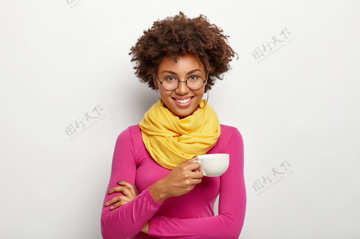 眼镜快乐表情的非洲裔美国女性肖像 戴眼镜 拿饮料杯 戴眼镜 粉色高领毛衣和围巾 孤立在白色背景上饮料深色浓咖啡