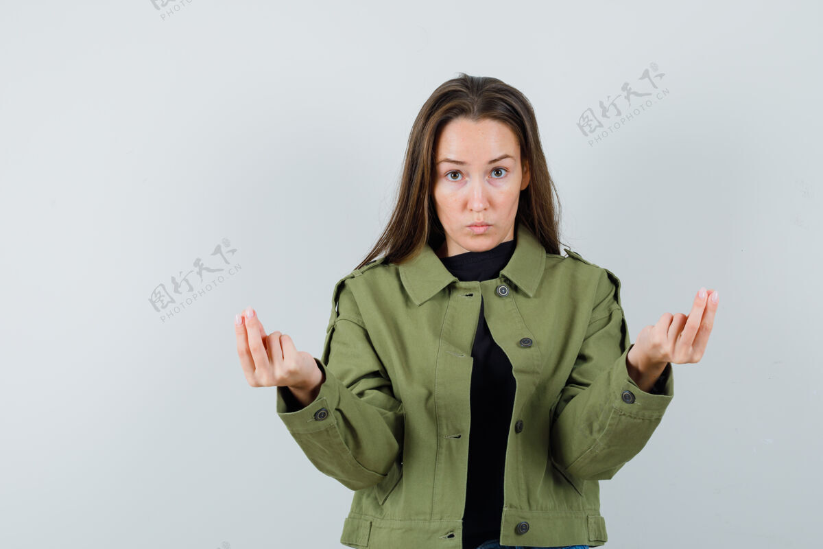 解释年轻女子在绿色夹克前视图中做着解释的手势时尚年轻东西