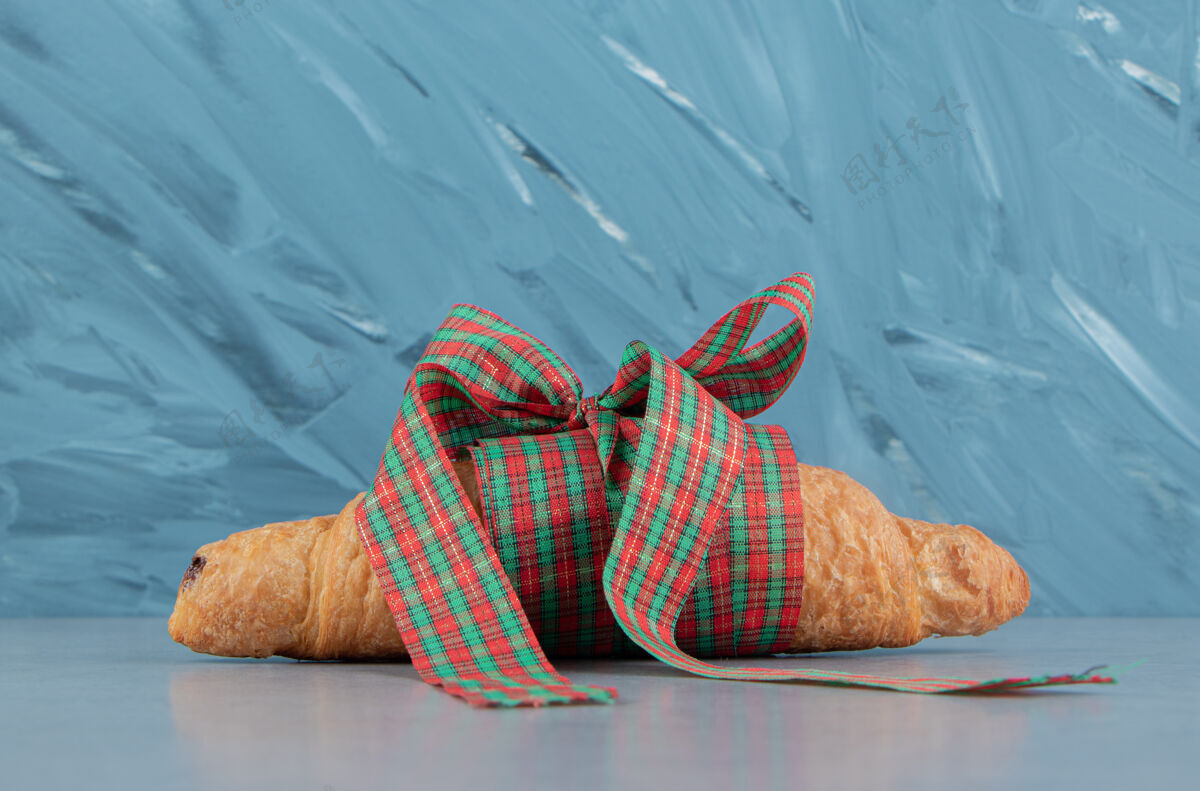 牛角包羊角面包用缎带绑在大理石背景上高质量的照片糕点美味甜食