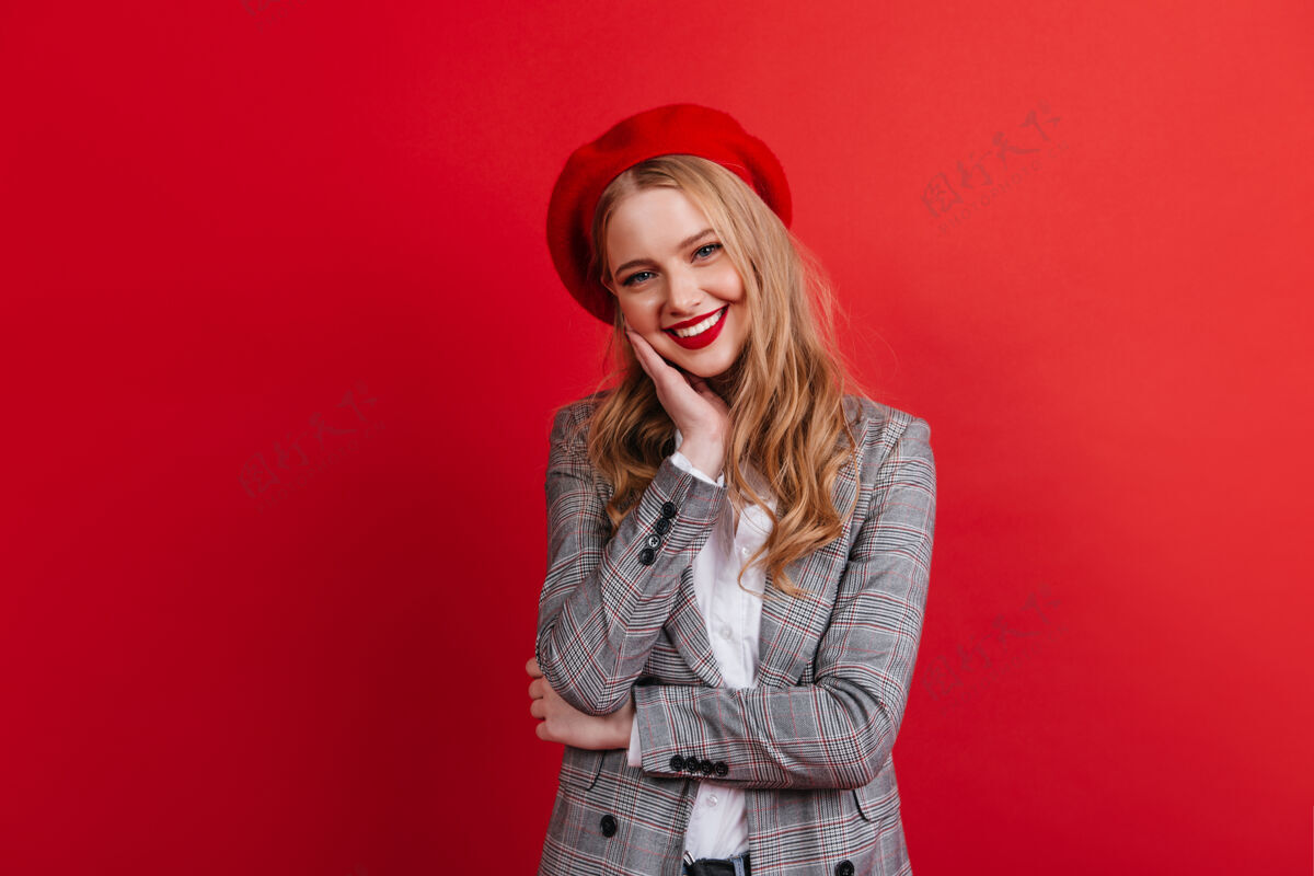 模特戴贝雷帽的可爱金发女孩微笑的欧洲女人被隔离在红墙上表情欢呼浪漫