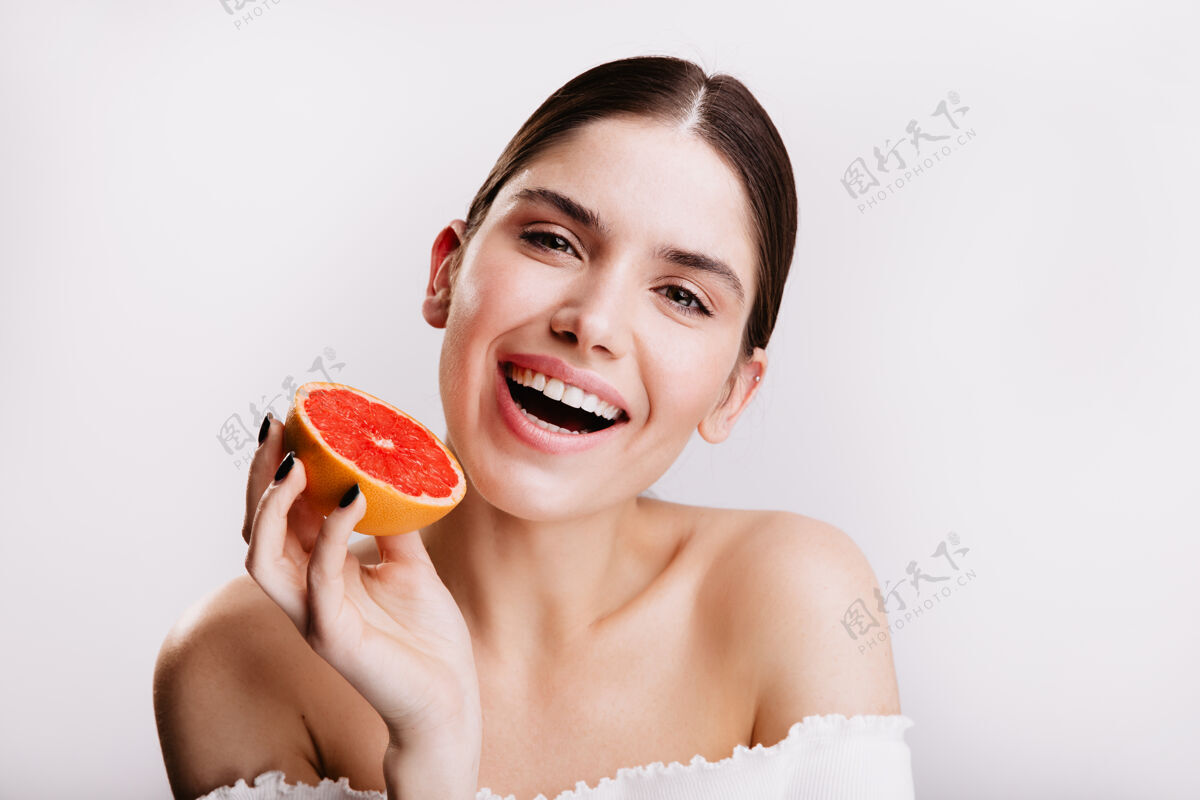 脸拥有完美干净皮肤和雪白笑容的女人的特写肖像模特摆出红色多汁柑橘水果的姿势肖像绿色眼睛成人