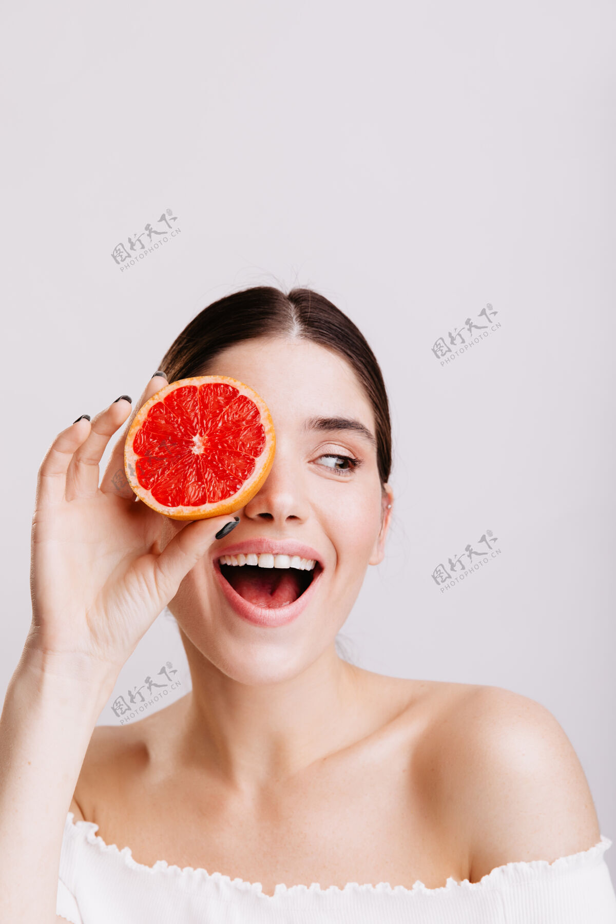 柑橘黑发女孩在白墙上微笑的画像没有化妆的女人和葡萄柚摆姿势皮肤护理漂亮积极