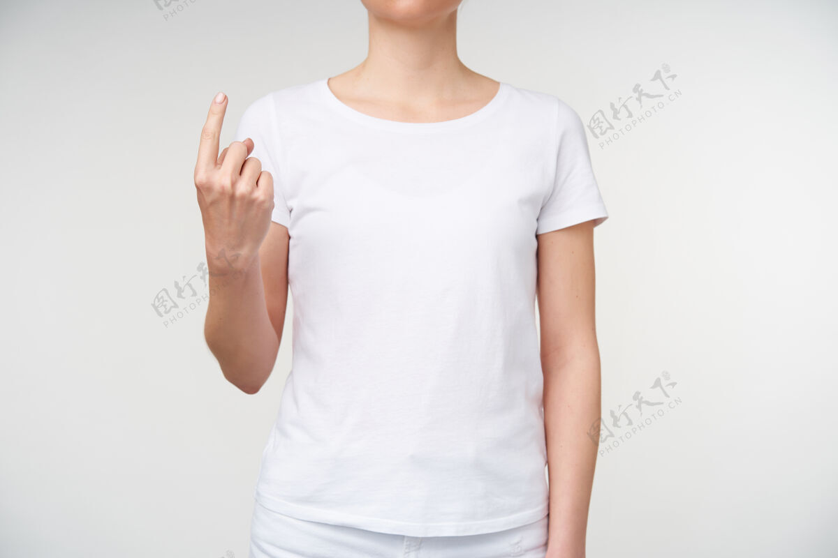 白色室内照片 年轻女士展示食指 同时在手语上表示单词的位置 隔离在白色背景上有听力障碍的人的手势符号站立休闲