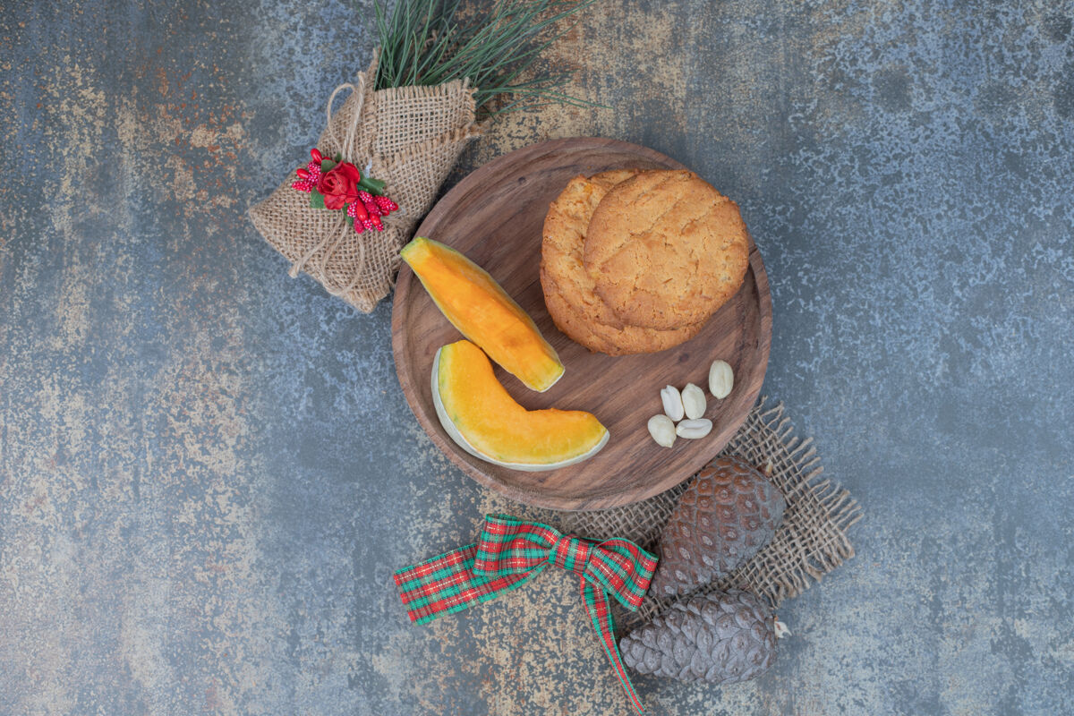 切片饼干和南瓜片放在装饰着丝带的木板上高质量的照片可食用松果南瓜