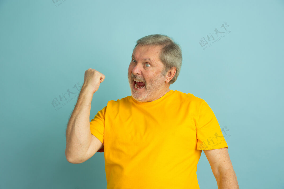 表情庆祝胜利 体育白人男子肖像隔离在蓝色工作室背景黄色衬衫摆姿势美丽的男模手势高级养老金